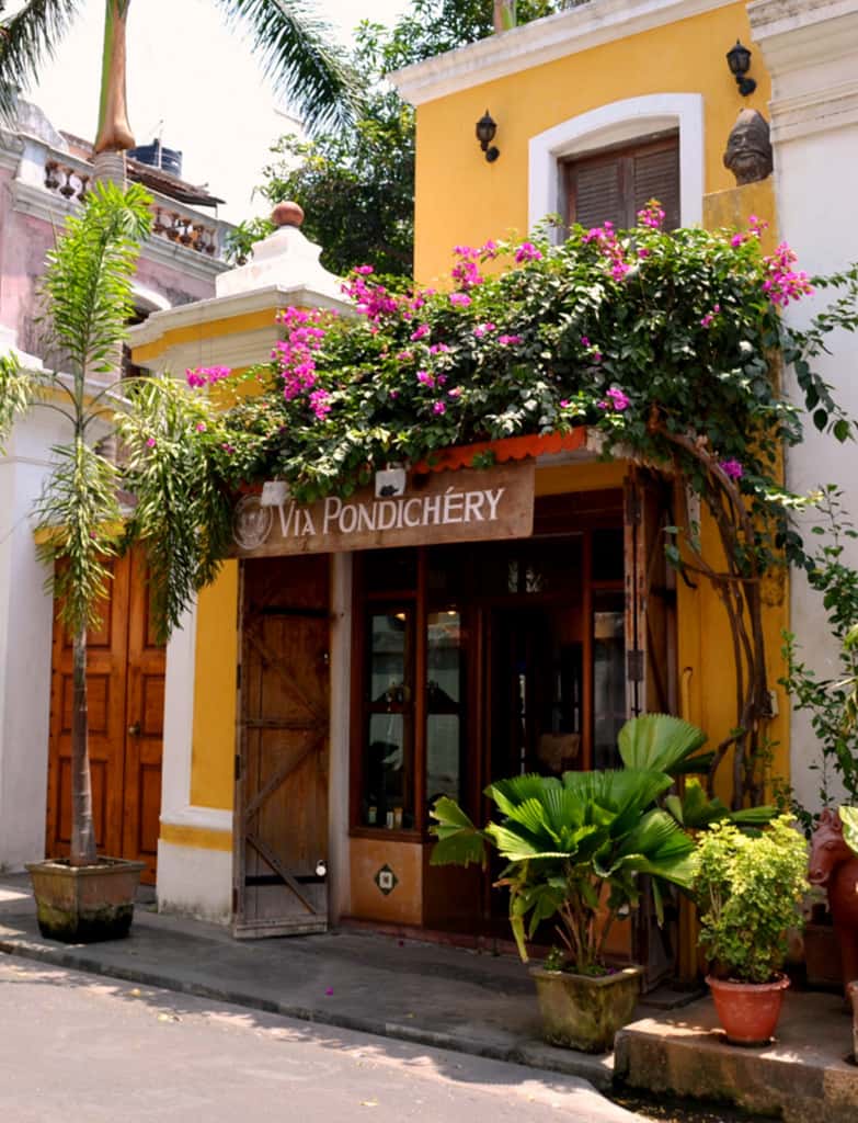 A yellow French-quarter building draped in bougainvillea, Pondicherry