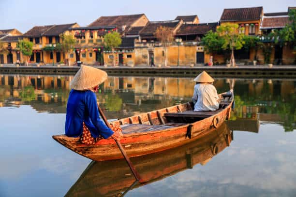 A woman in a conical hat rowing a boat in Hoi An, Vietnam