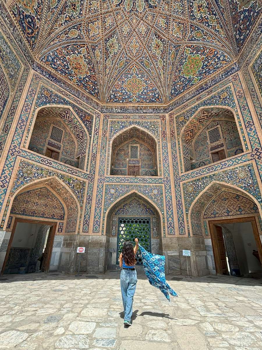 A traveller in a tiled madrasa courtyard, Uzbekistan